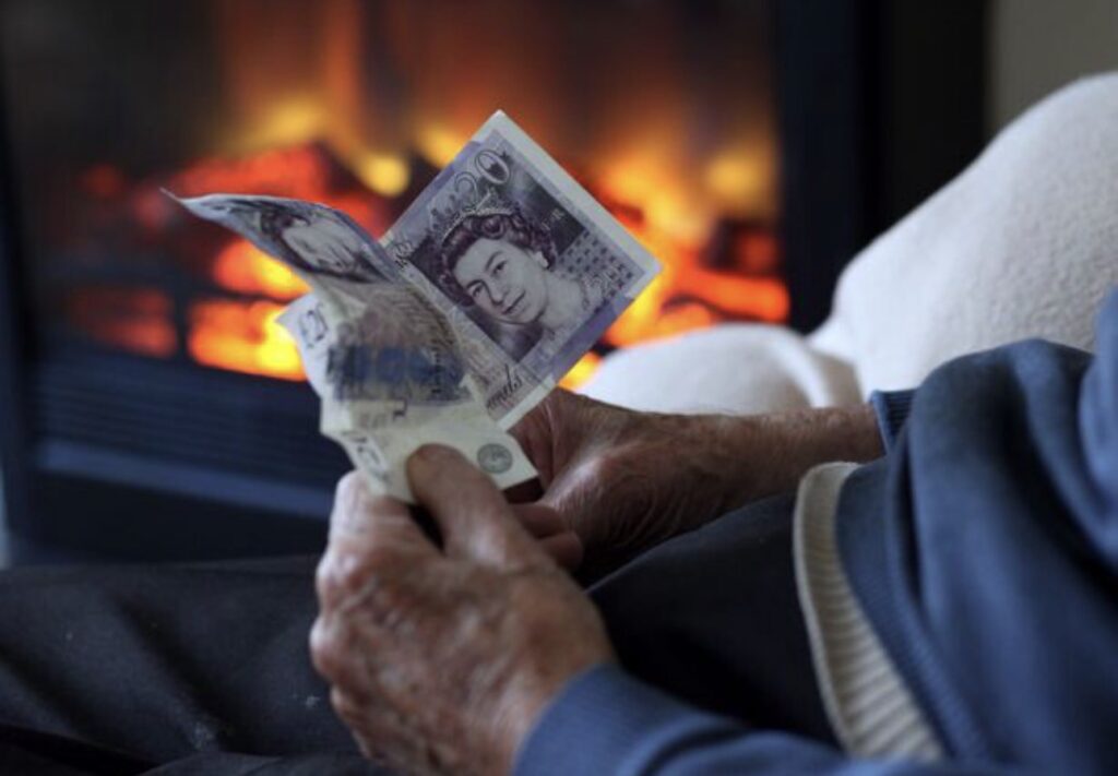 Hands holding British pound banknotes beside a fireplace
